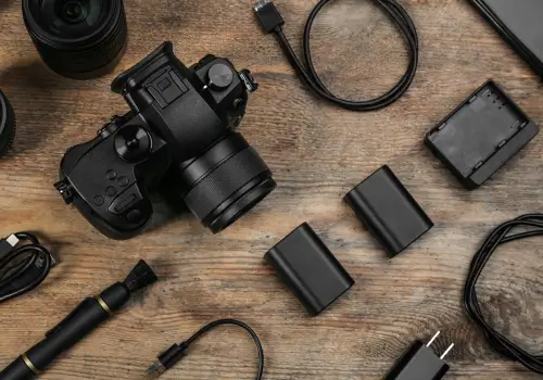 A digital camera and various accessories on a wooden table.