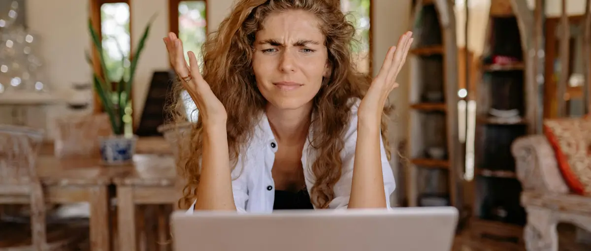 An image of a woman looking at her subscriptions on a laptop while frustrated