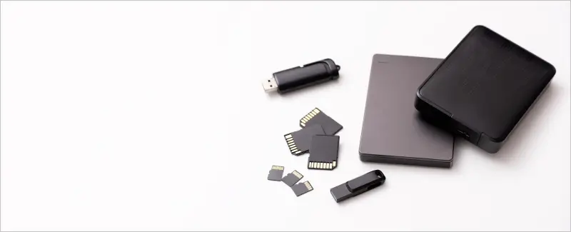 A collection of media cards, external drives, and USB sticks on a blank background.