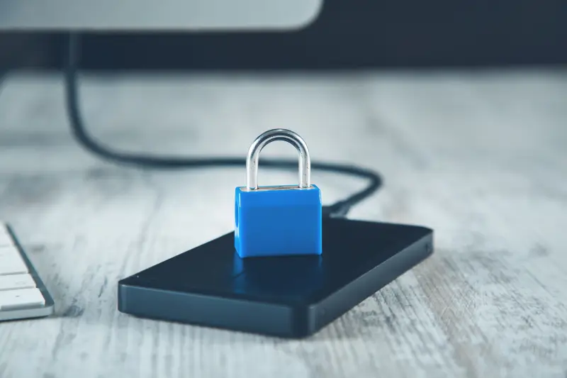 A lock sitting on an external hard drive to represent encryption.