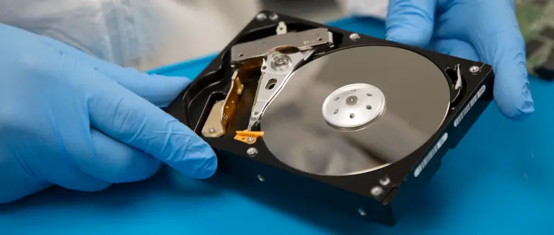 A data recovery engineer examining the internal components of a hard disk drive. 