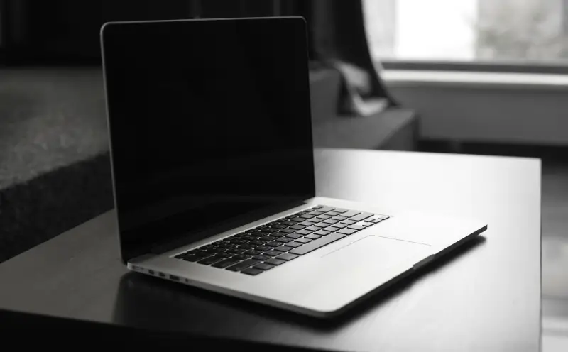 A MacBook with a black screen sitting on a table.