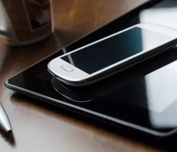 An image of a smartphone and tablet sitting on a table.